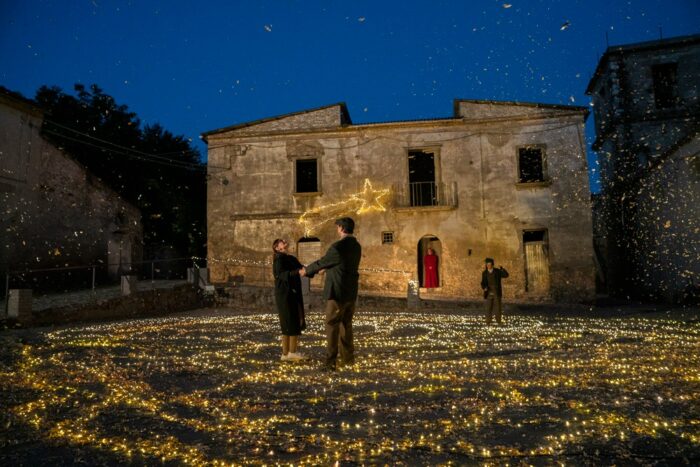 Un treno porta a destinazione un attore e una famiglia di senzatetto. Il loro viaggio non è solo la ricerca di una casa ma una messa in scena: l’attore prende le vesti di un Dante che nessuno accompagnerà nella sua discesa all’inferno, la famigliola vaga alla ricerca della casa promessagli.
Di volta in volta, un numerologo prova a trovare un senso a tutta questa commedia, a raccontare il viaggio tra i gironi infernali e le grotte del presepe, tra l’arte popolare e quella di ricerca. Il conte Ugolino e Paolo e Francesca raccontano le loro pene, tra aneddoti della storia della fotografia e della pittura, tra simboli e parole, tra Pontormo e Glenn Gould. Dante, ammutolito, passa tra guerre, bestemmie e miserie, in un viaggio dentro il tempo e lo spazio della creatività e delle idee più eretiche. La povera famiglia cerca solo un riparo e un tozzo di pane, ma la sua più che una ricerca sembra sempre più un indovinello. Intanto tutte le arti giungono sul tavolo della messa in scena, portate da un gruppo di Magi smarriti e arrivati tardi all’appuntamento, bisogna donare qualcosa e tra loro c’è chi porta il teatro, chi la musica e chi il nulla. Chi cercano? Si arriverà a riveder le stelle? Il viaggio di ciascuno dei personaggi è un unico andare, guidati da una divina cometa, in un’ascesa dal fondo dell’inferno fino al paradiso.